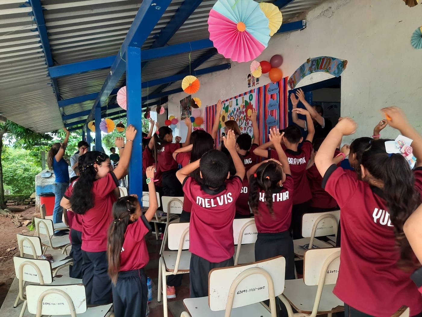 Students with their hands in the air during a celebration under the school's covered area