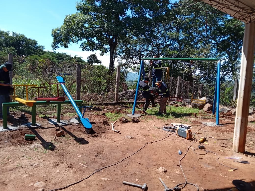 Workers installing swings and a seesaw at the school playground